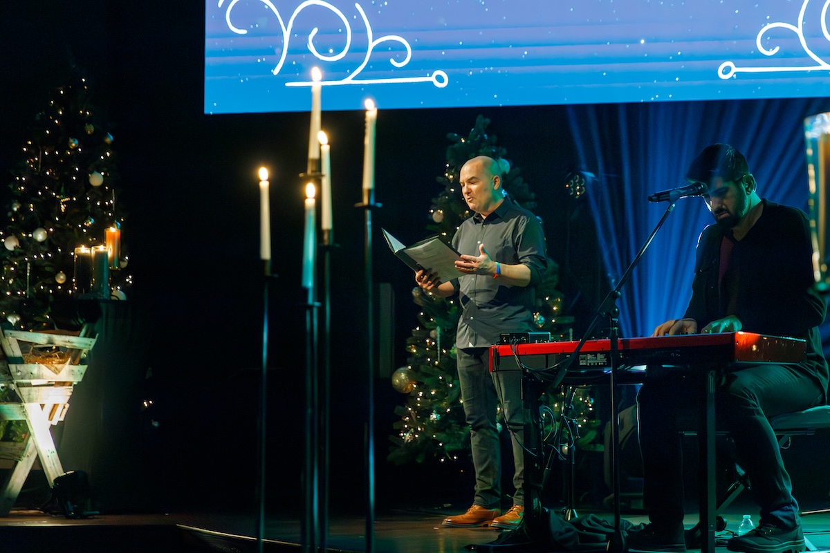 ChristmasEve_2024-CJones-67-1 pastor preaching from stage on christmas eve, with lit candles in the foreground
